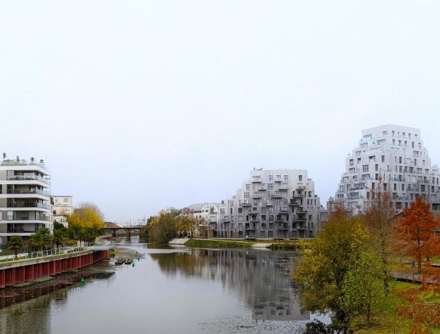 A river surrounded by residential buildings. The sky is grey / white.